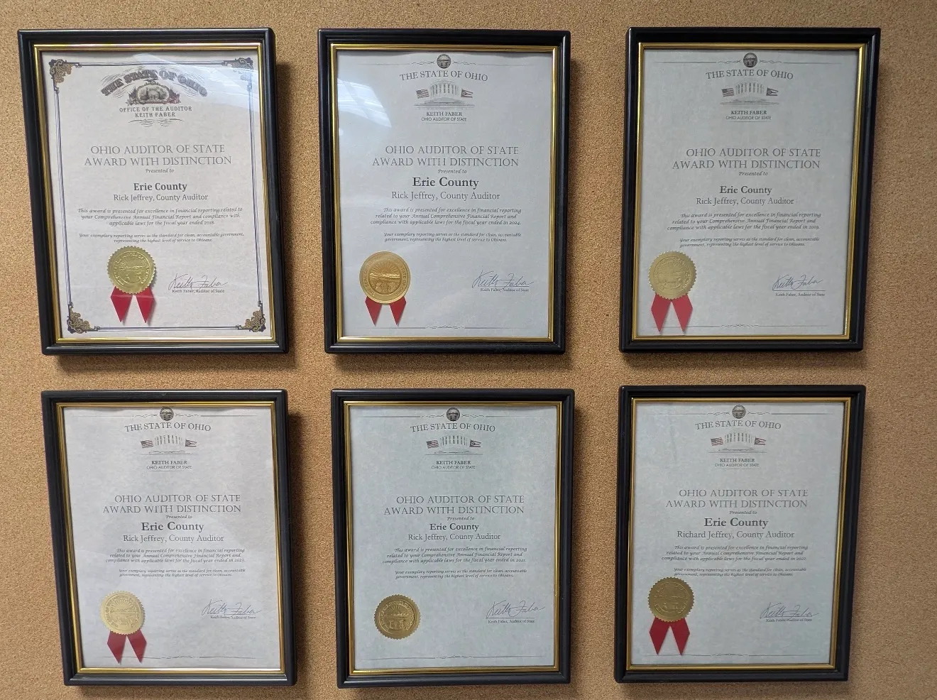 Six framed Ohio Auditor of State Award with Distinction certificates presented to Erie County and Rick Jeffrey, County Auditor, displayed on the office wall